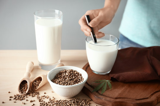 Woman with glass of hemp milk on table