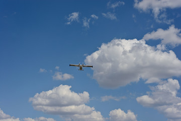 Light airplane against the blue sky with white clouds background