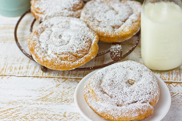 Swirl Danish Pastry Ensaimada Powdered on Cooling Rack and Plate. Bottle of Milk White Plank Wood Tabletop. Rustic Kitchen Interior. Top View