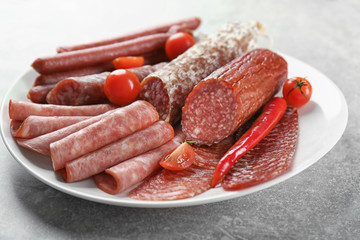 Plate with delicious sliced sausages on table