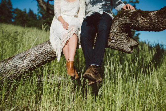 man and woman's feet dangling from a tree they sit in.a