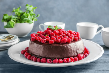 Tasty chocolate cake with raspberries on table
