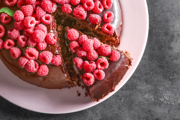 Sliced chocolate cake with raspberries on table
