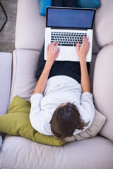 Young woman using laptop at home top view