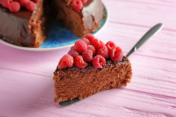 Piece of tasty chocolate cake with raspberries on table
