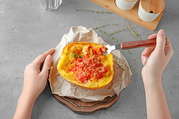 Woman eating tasty stuffed spaghetti squash at table