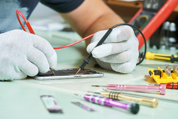 smart phone repair. repairman testing electric circuit