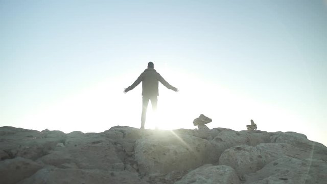 Man standing on a desert cliff with his arms open