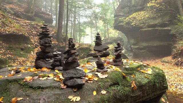 CLOSE UP: Stone sculpture on mossy rock left by travelers as a spiritual memento. Pile of stacked stones in gorgeous Hocking Hills State Park, Ohio, America. Rocky sculptures in foggy autumn woods