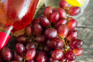 Bunches of fresh different ripe grapes and a bottle of rose wine on  wooden textural surface. space for advertising text 