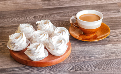  white marshmallows (zephyr) on a round wooden board with cup of coffee