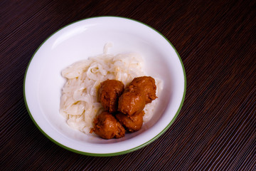 Kuey teow and meatballs  in a white bowl on the table