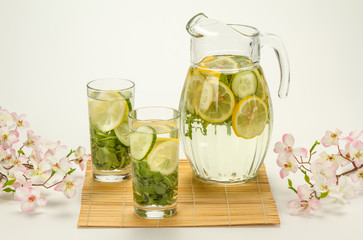 refreshing drink with lemon and seasonings in the summer morning with flowers