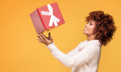 Afro girl posing with gift box, smiling.