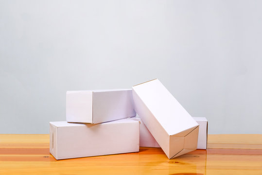 Empty four Package white cardboard box for long items on wooden table with copy space.