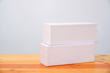 Empty two Package white cardboard box for long items on wooden table with copy space.