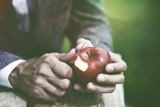male hands peeling red apple with knife