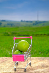 Shopping cart and limes  with blurred background. Conceptual image of buying vegetables and healthy eating.