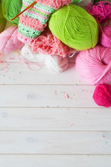 Yarn, candles, knitting on a white background wood. Pink and green colors.