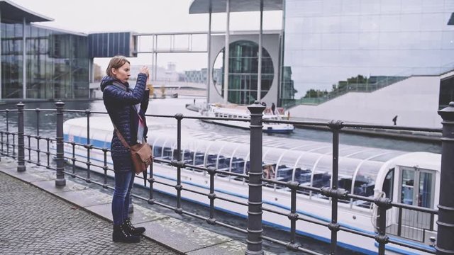 Woman Taking Pictures of German Chancellery - Bundestag Building - in Berlin with SmartPhone. SLOW MOTION. Attractive young woman tourist with cellphone outdoors. Travel in Germany.