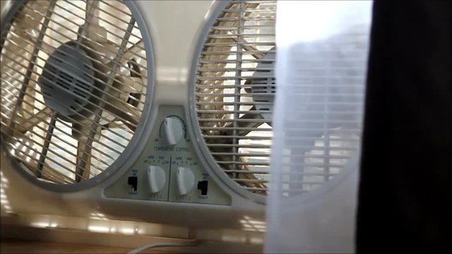 man's hand turns a fan down