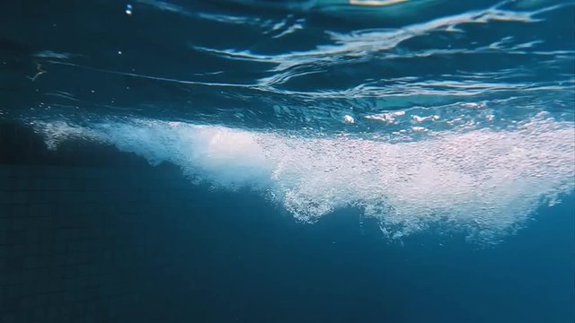 Bubbles in swimming pool underwater slow motion. Deep and blue water natural bubbles shot.