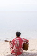 Fototapeta na wymiar asian man playing guitar at the beach