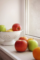 Fresh fruits and colander on windowsill