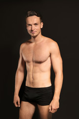 Young man in underwear on black background