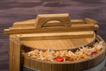 salted cabbage and carrots in an oak barrel, on a wooden background
