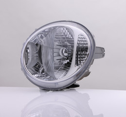 round car headlight on bright background with reflection. isolated 