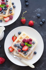 Belgium waffles with fresh berries on white plate. Top view