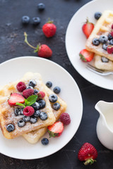 Delicious Belgian waffles with mint leaf and berries on dark background with copy space