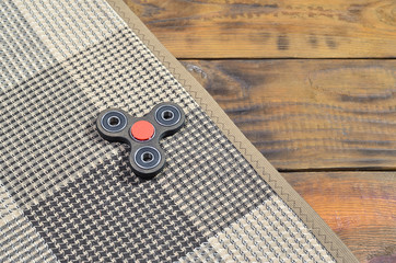 A rare wooden handmade spinner lies on a checkered plaid on a brown wooden background surface....