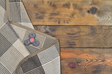 A rare wooden handmade spinner lies on a checkered plaid on a brown wooden background surface....