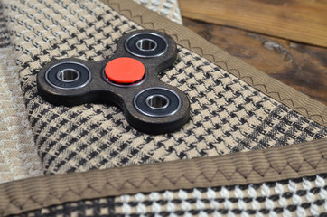 A rare wooden handmade spinner lies on a checkered plaid on a brown wooden background surface....