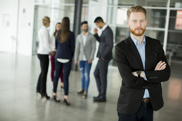 Businessman standing in the office and other business people talking