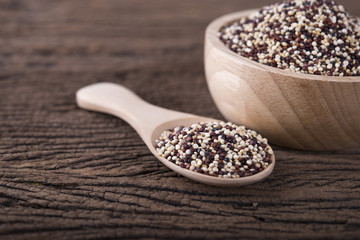 dry tricolor quinoa in wooden spoon and bowl on wooden background
