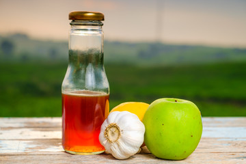 Fresh organic honey in glass jar , garlic, lemon and green apple on old wooden with blurred background , healthy nutrition, strengthening immunity and treatment of flu