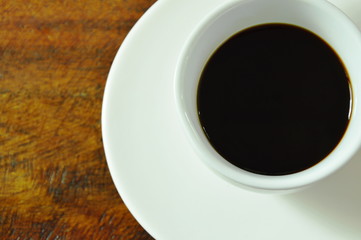 black hot coffee cup in plate on wooden table