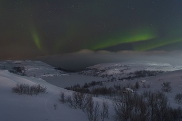 The snow covered the hills and in the sky the stars and the aurora borealis.