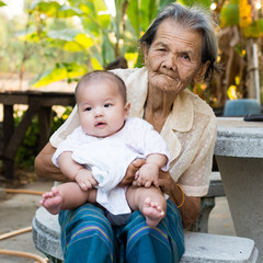 Great-grandmother holding adorable baby great-granddaughter in her arms