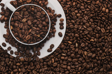 White cup with coffee beans. Coffee in beans macro. Abstract background texture.Coffee beans texture. Food background of coffee beans