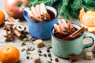 Mulled wine with Apple, citrus, cinnamon, cardamom and star anise on wooden background. Traditional...