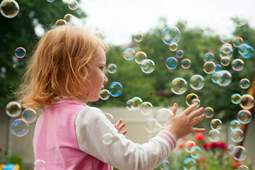 Red-haired girl catches soap bubbles