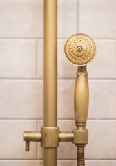Bronze shower mounted on a rack on a beige background tile