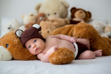 Little newborn baby boy, sleeping with teddy bear at home in bed