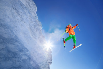 Skier jumping against blue sky from the rock