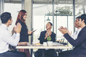 Business Partners clapping hands to a success business woman after complete a deal.