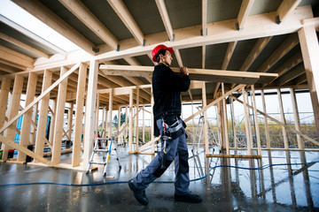 Profile Shot Of Carpenter Carrying Wood At Site